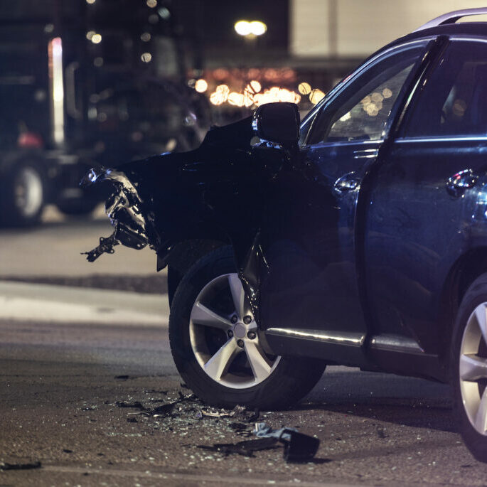 Traffic Accident Automotive Collision at Night. Heavy Damaged Modern Car on a Street. Transportation Safety Theme. Car Crash.